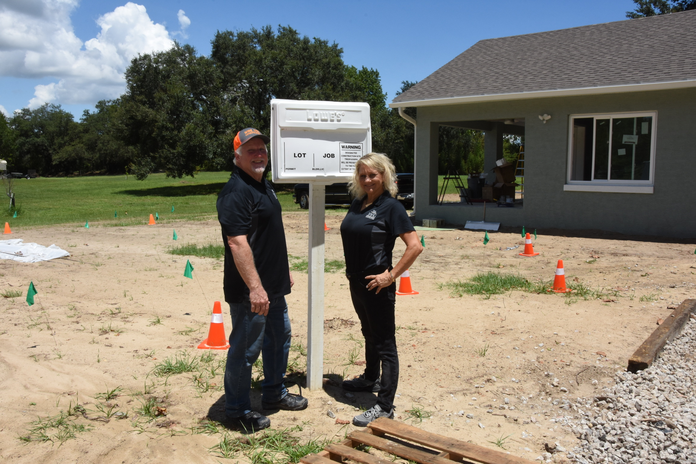 Kurt and Lana Gies standing beside a Wise Gies Construction job site sign