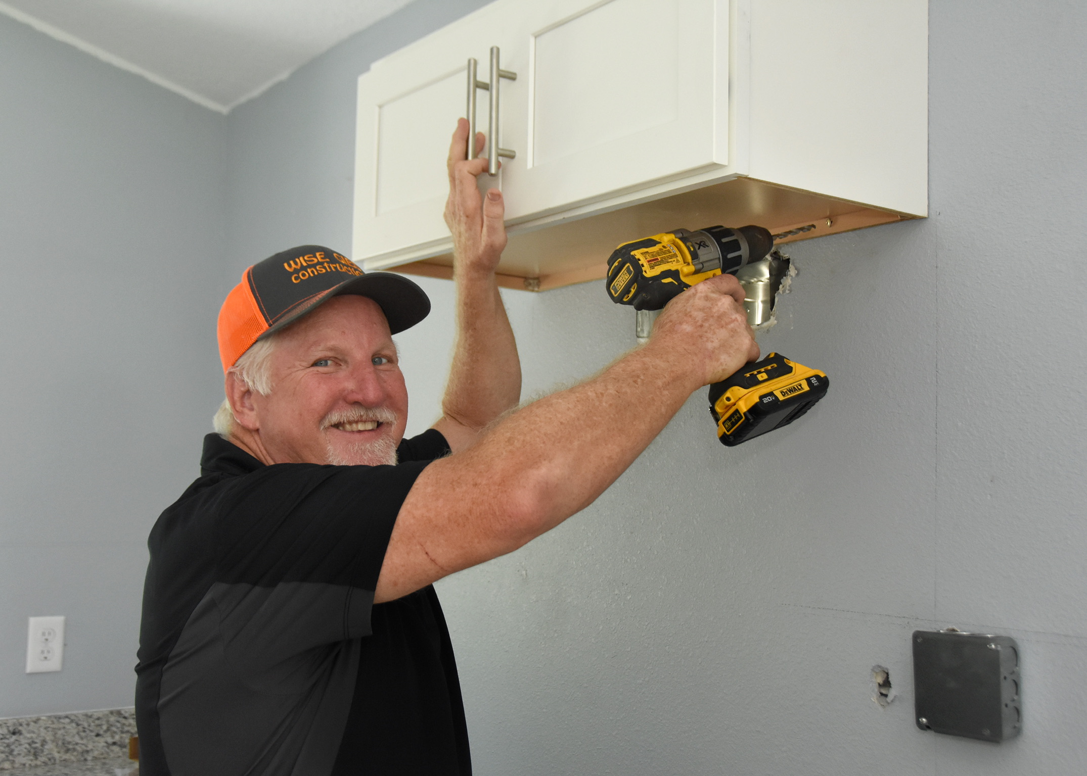 Kurt Gies installing cabinetry with a drill on a job site