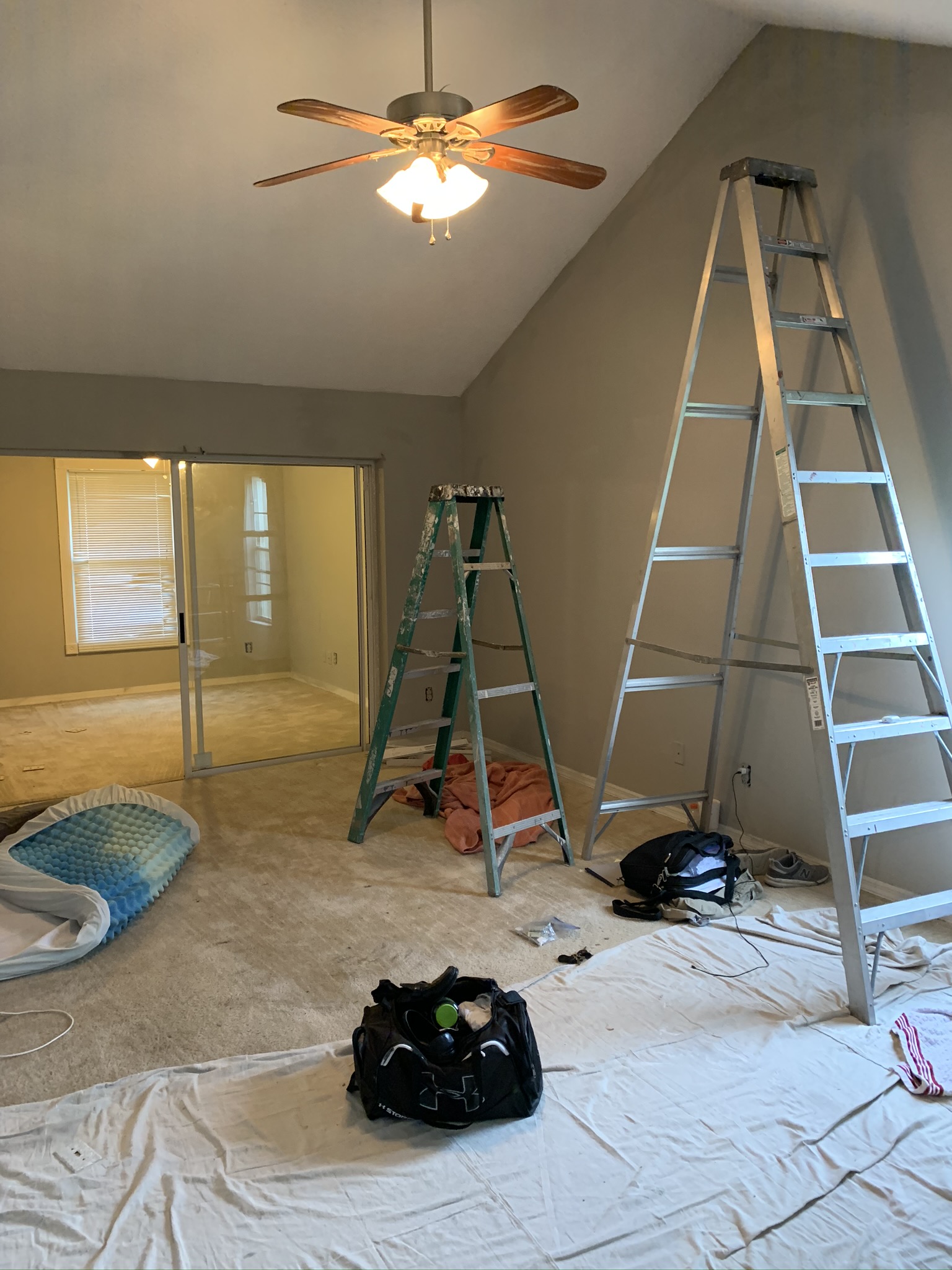 Interior room being repainted with ladders and drop cloths in place