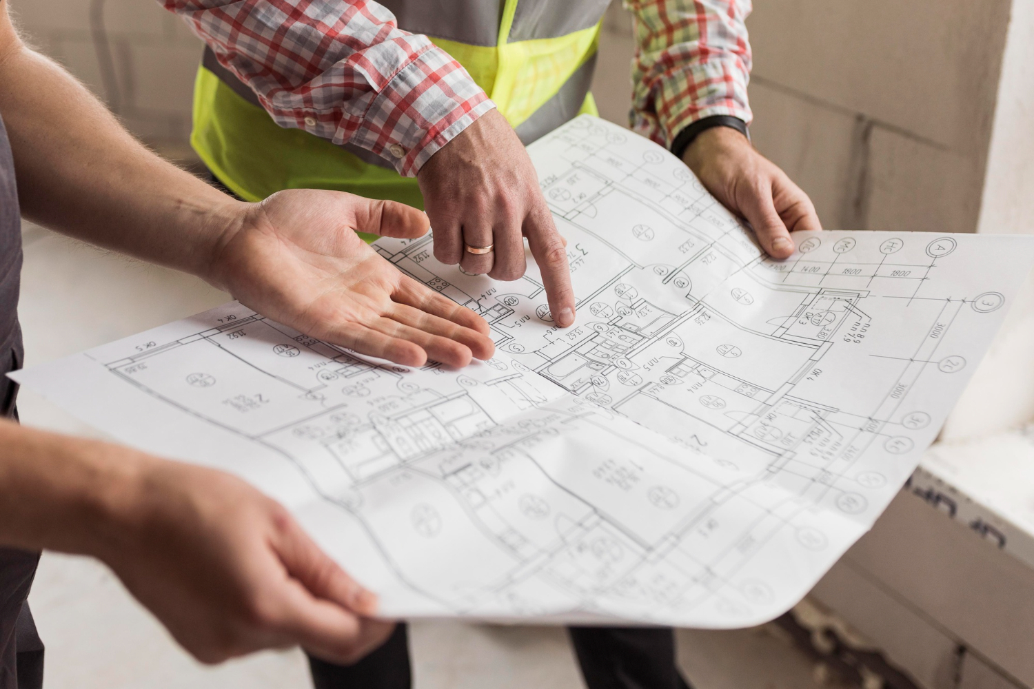 Hands pointing over architectural blueprints during a pre-construction planning meeting