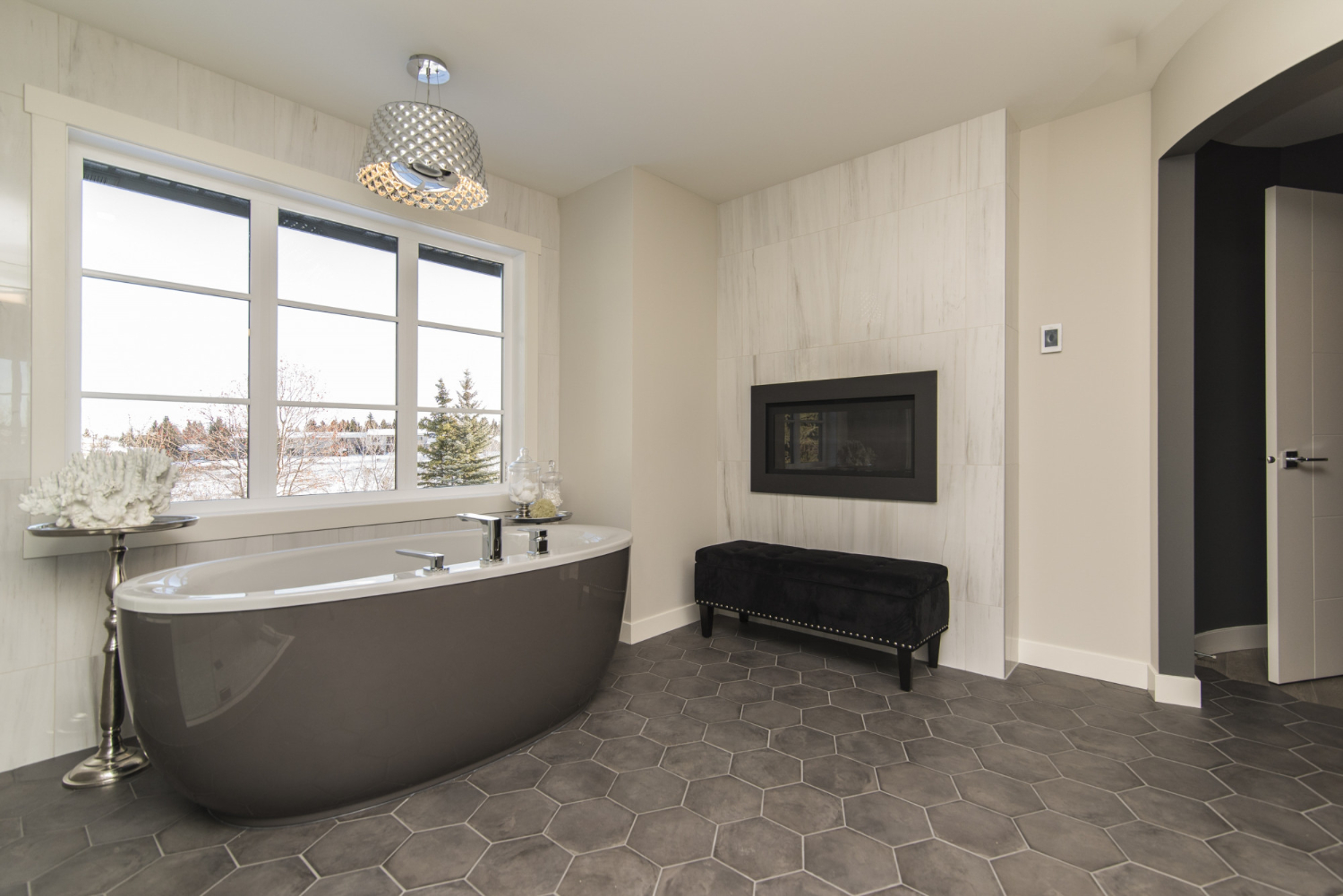 Remodeled bathroom with freestanding soaking tub and tile fireplace wall